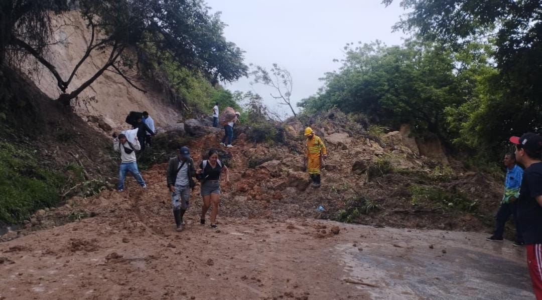 Un deslizamiento de tierra bloquea la vía principal en el Pacífico nariñense, mientras habitantes de la zona atraviesan con cautela entre las piedras y el barro.