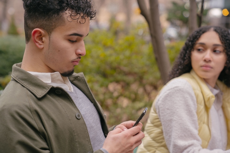 Pareja utilizando teléfonos móviles mientras una persona oculta la relación en redes sociales, representando el fenómeno conocido como pocketing.